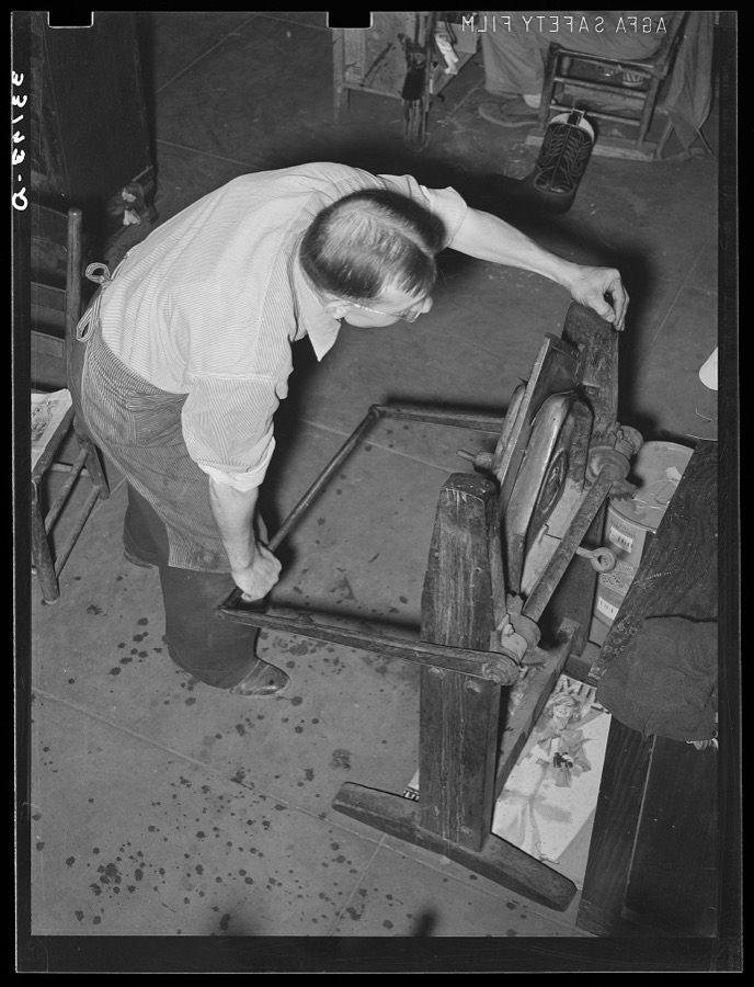 Crimping is accomplished by pulling down the lever on the crimping machine. Bootmaking shop, Alpine, Texas