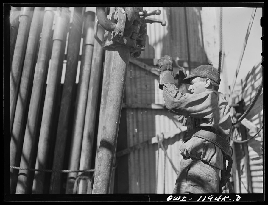 Andrews County, Texas. Derrick man putting pulled drill pipe in place. He is 120 feet above the ground