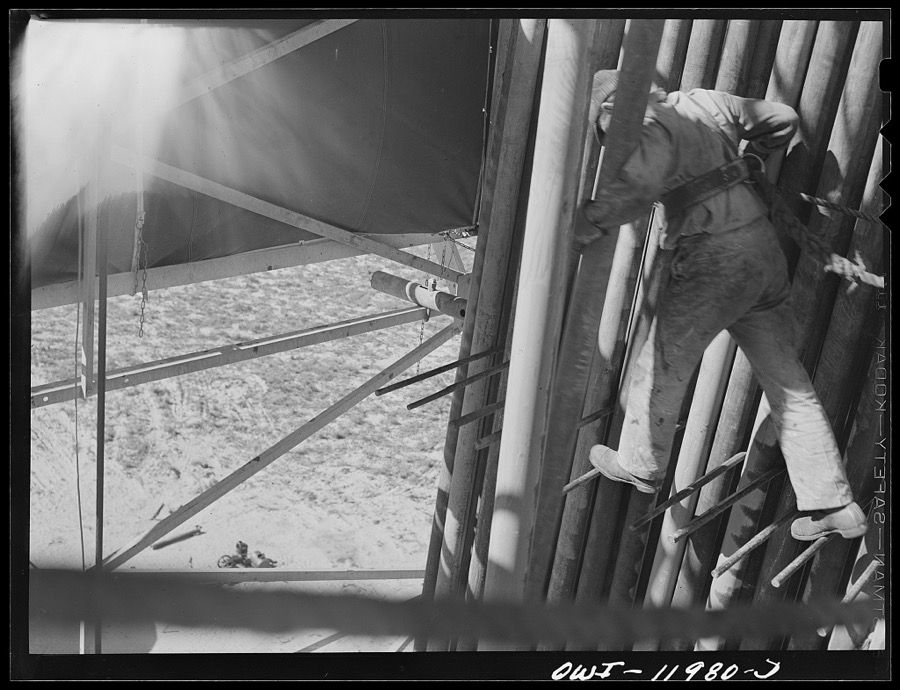 Andrews County, Texas. Derrick man putting pulled drill pipe in place. He is 120 feet above the ground