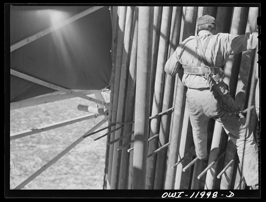 Andrews County, Texas. Derrick man putting pulled drill pipe in place. He is 120 feet above the ground
