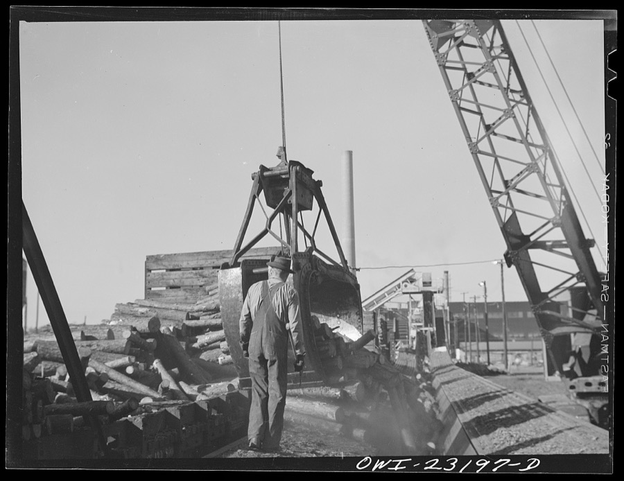 Lufkin, Texas. Southland paper mill. Crane unloading flat car of pulpwood in the wood yard
