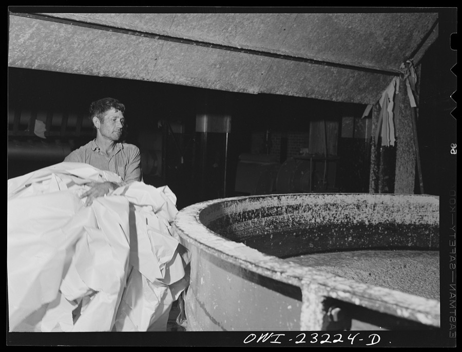 Lufkin, Texas. Southland paper mill. Placing trimmed edges of newsprint rolls into a vat where they are converted back into stock