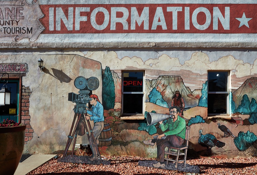 The Kane County Tourism Office in Kanab, a small city on the Arizona border in southern Utah, doesn't just talk or give visitors brochures about the town's rich history as the gathering place for producers, actors, and crews producing iconic western movies in the colorful canyons nearby, it illustrates that tradition on its exterior walls too